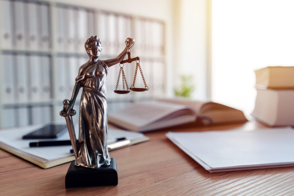 Law firm trust accounting. Lady Justice statue in law firm attorney office, blindfolded Justitia with balance scales and sword is personification of moral force in judicial system.
